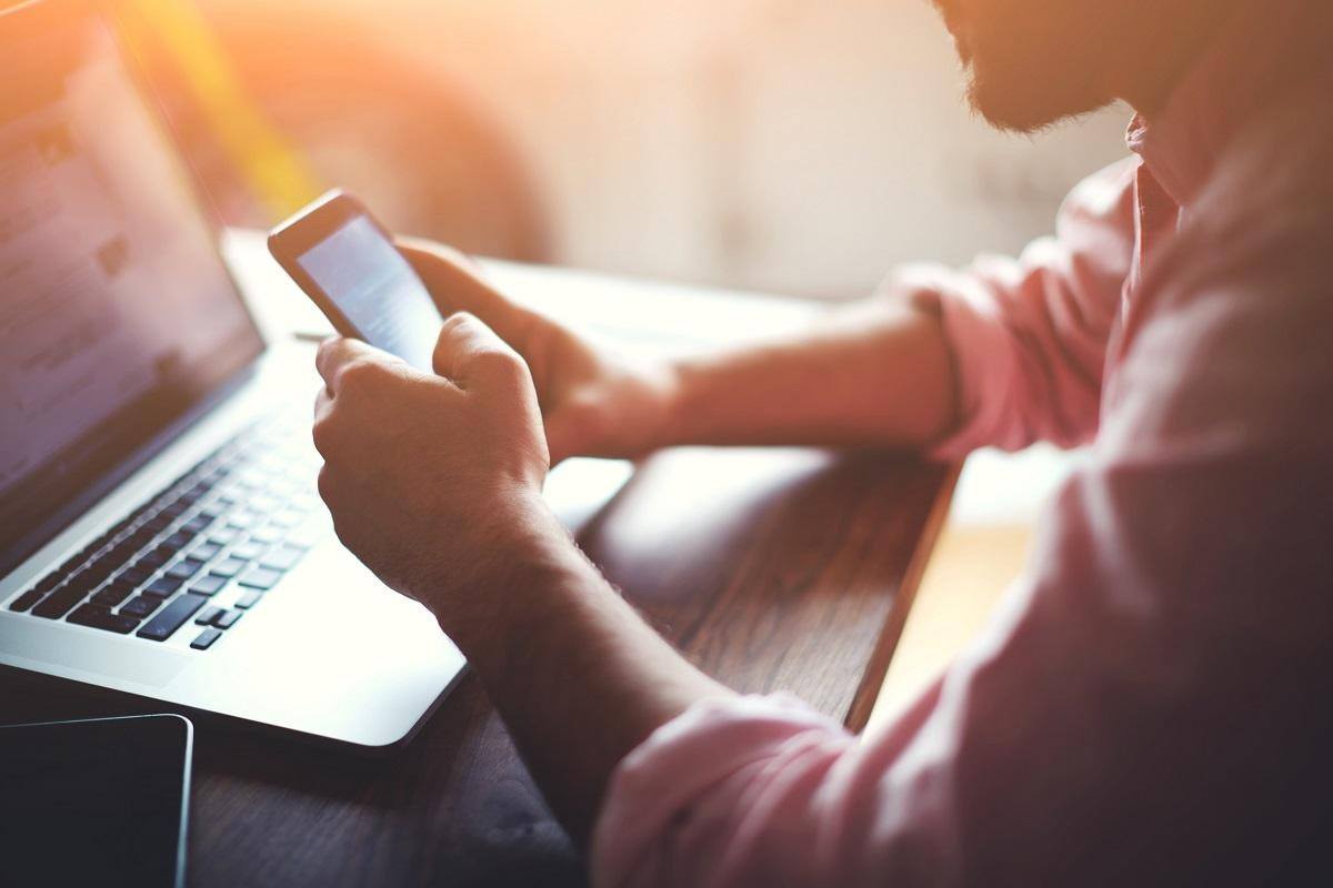 man on mobile phone in front of open laptop ways to improve time management