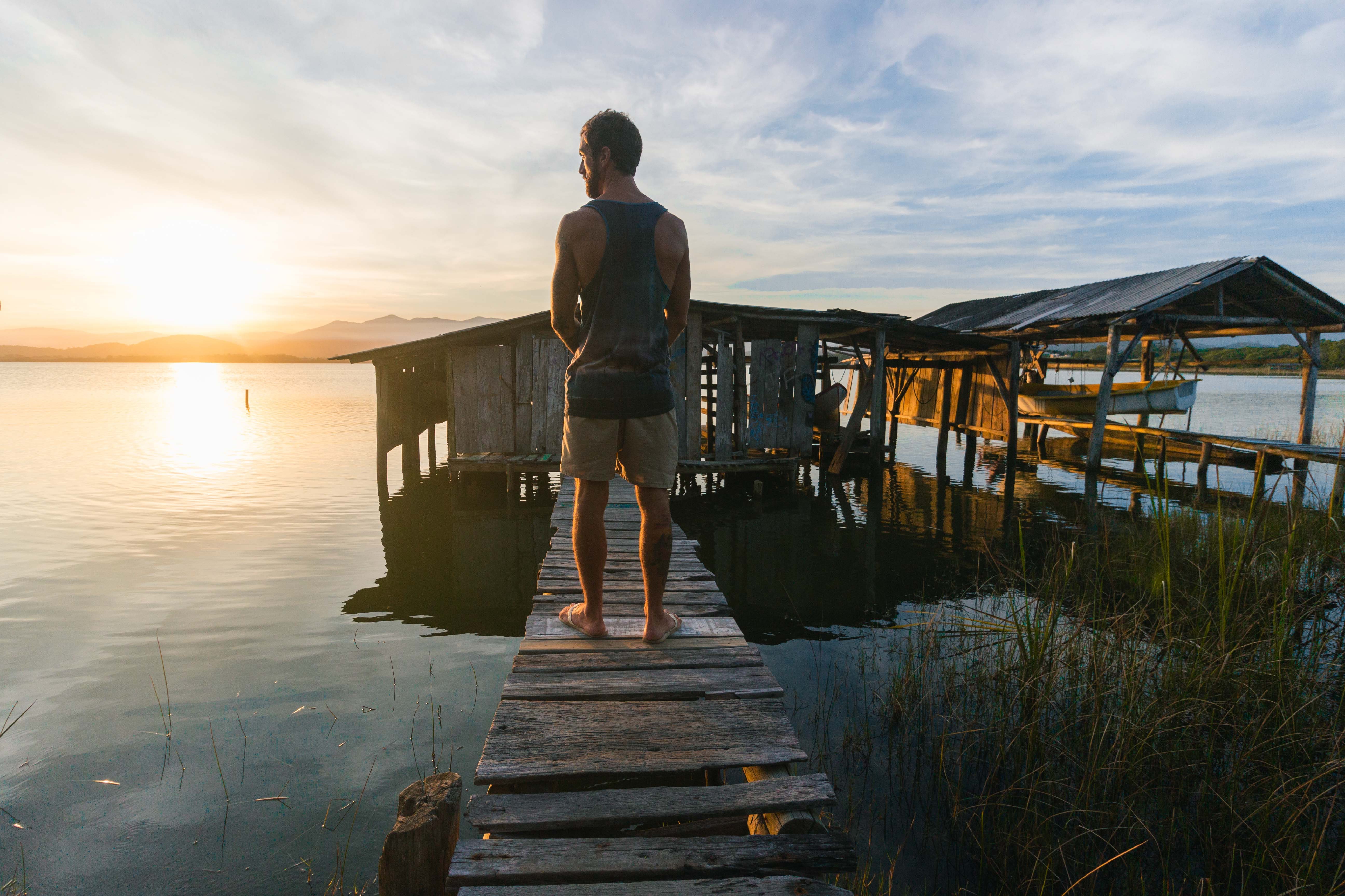 man on a pier at sunset looking meditatively how do i become successful