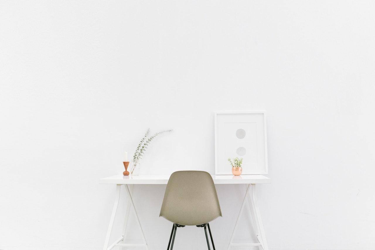 white table against white wall with beige chair under itwhite picture frame benefits of minimalism